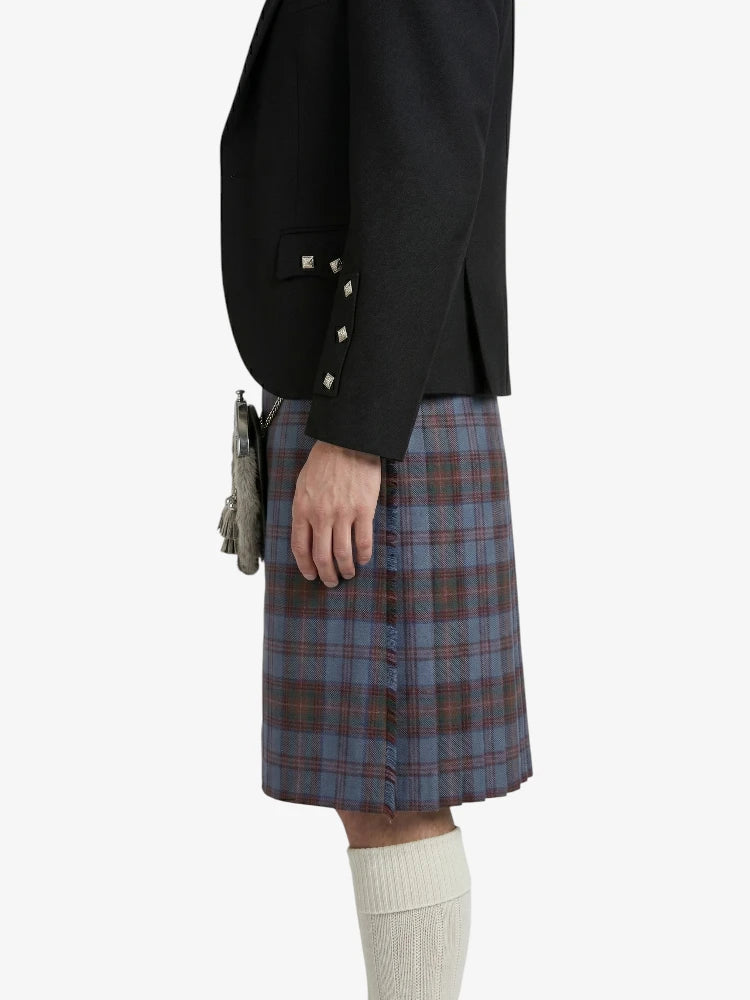 Person wearing a black blazer and plaid kilt on a white background