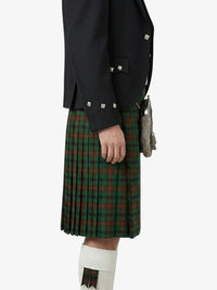 Person wearing a dark jacket and green plaid kilt on a white background