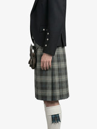 Person wearing a black jacket and plaid kilt on a white background