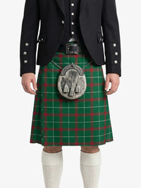 Person wearing a traditional Scottish kilt with a green plaid pattern on a white background
