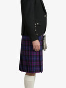 Person wearing a black blazer and purple plaid kilt on a white background
