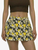 Person wearing a camouflage skirt with yellow and gray patterns on a plain background